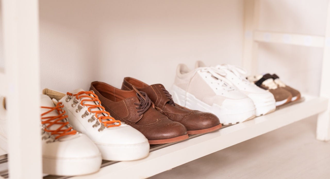 Sapatos organizados em prateleira, incluindo par de camurça marrom, ilustrando dica prática de como limpar camurça sem danificar o material.