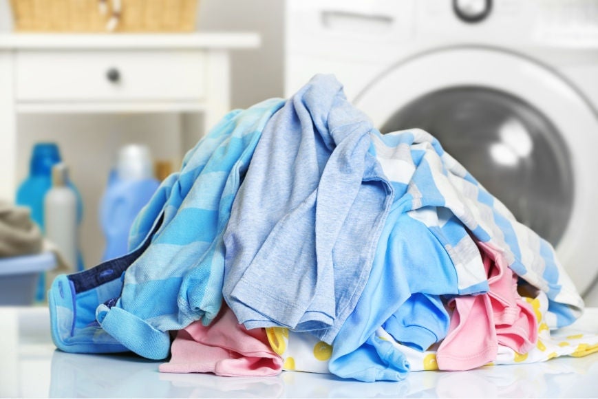 Pessoa colocando o sabão na máquina, demonstrando como lavar roupa preta para manter a cor vibrante por mais tempo.