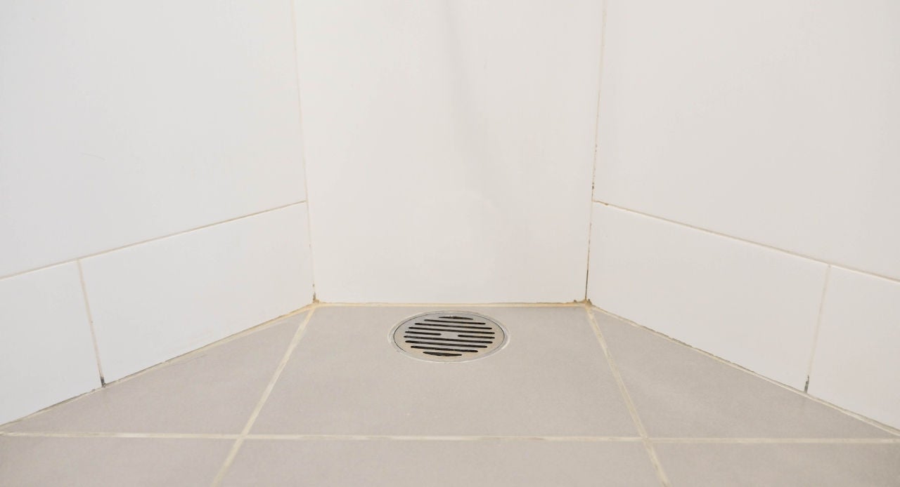 Ralo de banheiro com rejunte sujo e sinais de umidade, possível causa de mau cheiro no ralo do banheiro.