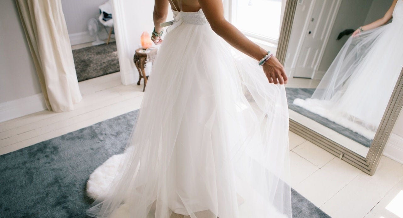 Mulher com vestido de tule branco em frente ao espelho, destacando os cuidados necessários em como lavar vestido de festa.