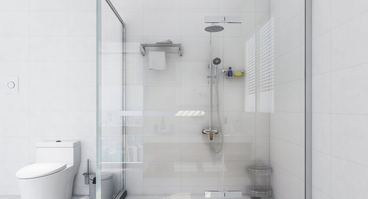 Banheiro branco com box de vidro transparente, chuveiro e acessórios, ilustrando dicas práticas de como limpar box de vidro.