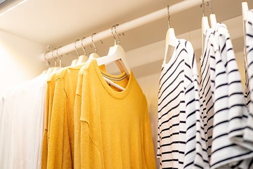 Roupas como novas organizadas em cabides de uma pessoa que aprendeu a como tirar bolinhas das roupas