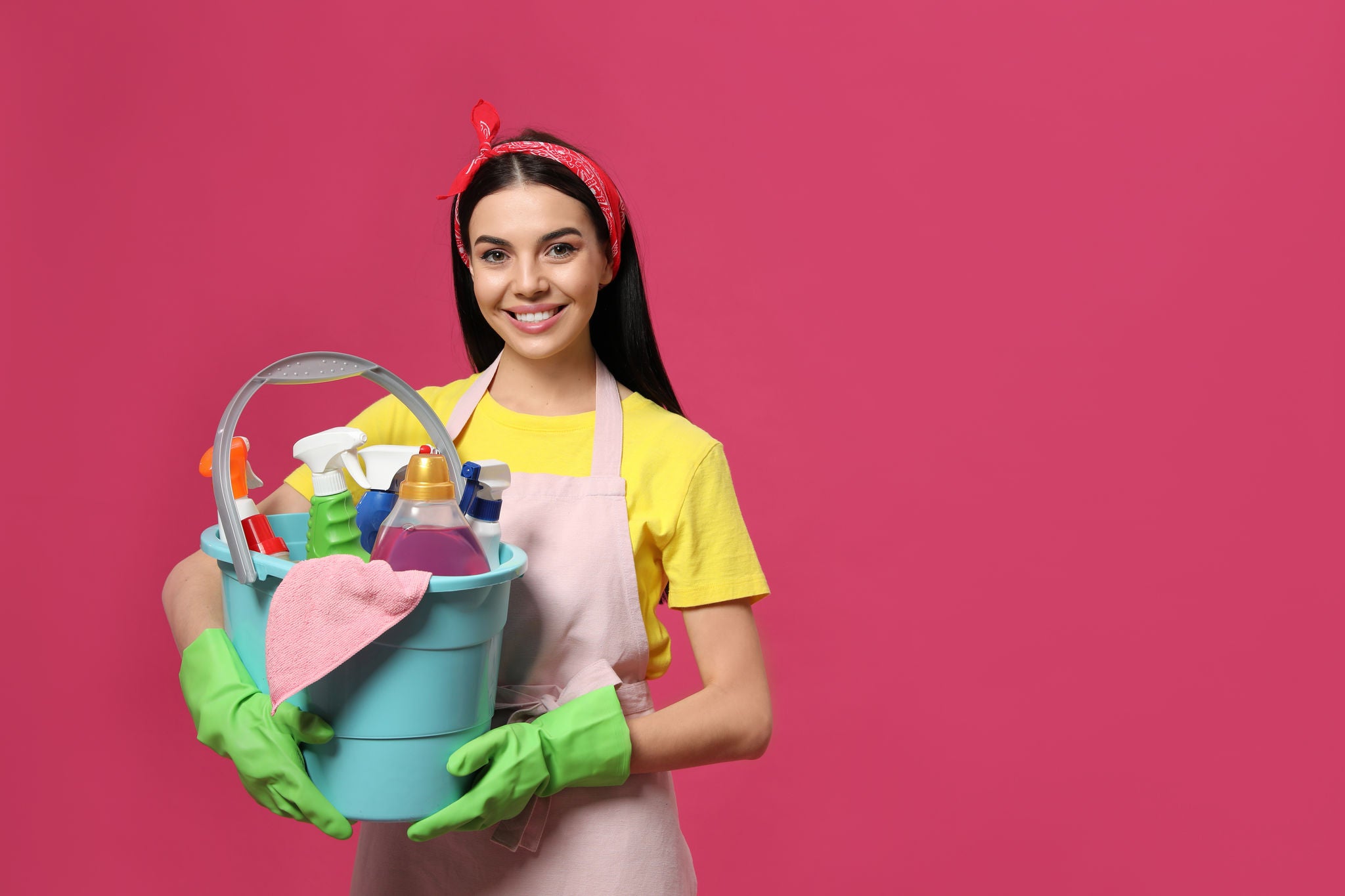 Mulher segurando alguns produtos de limpeza dentro de um balde, entre eles, o desinfetante caseiro.