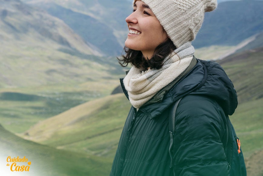 Mulher sorrindo nas montanhas, agasalhada e feliz após seguir guia de como lavar bobojaco
