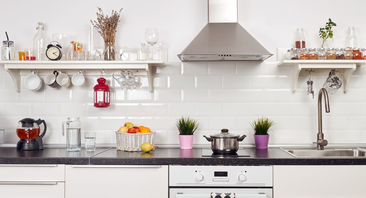 Cozinha moderna, branca e organizada, com utensílios, temperos e decoração, ilustrando dicas de como organizar a cozinha.