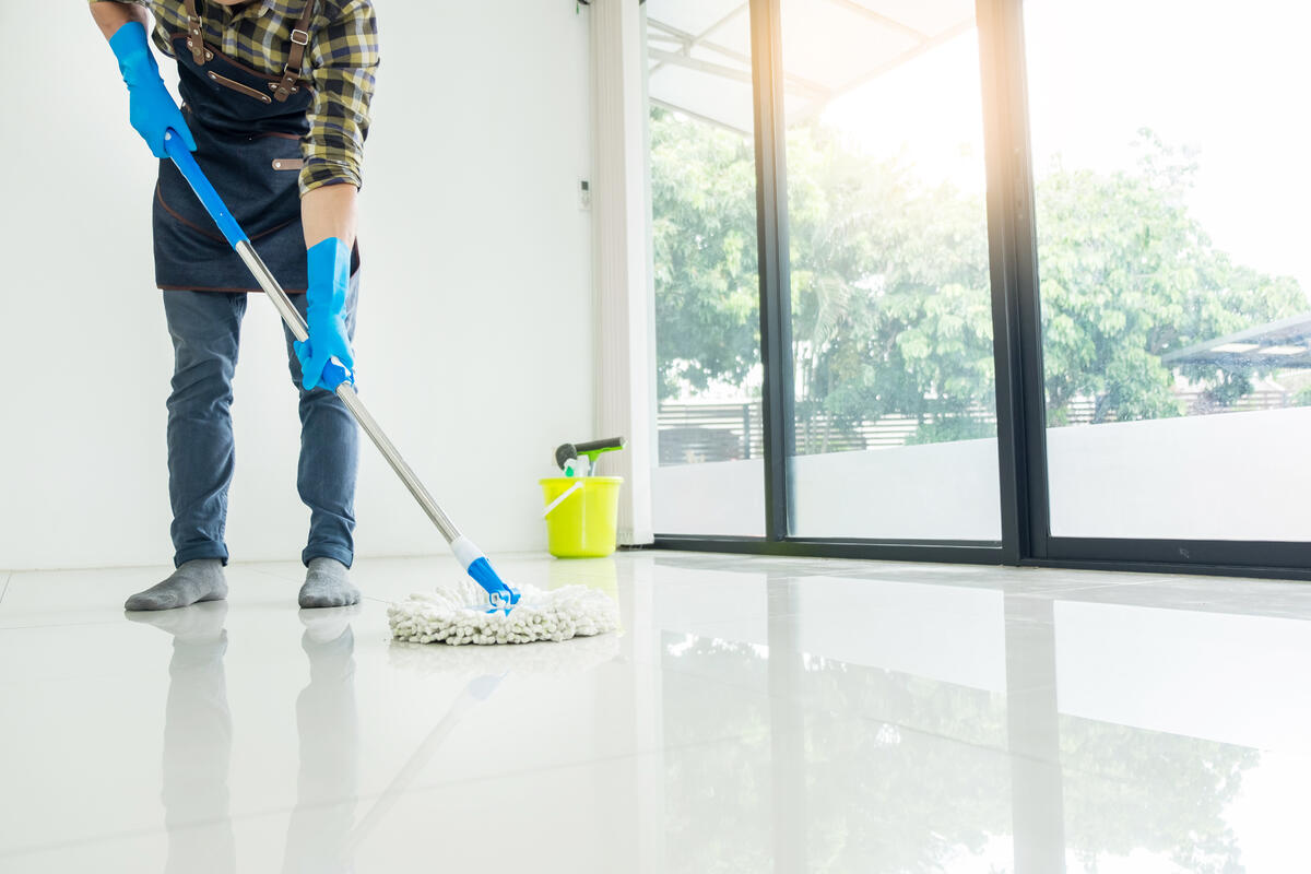 Homem limpando a casa depois de descobrir dicas incríveis de como tirar mancha de porcelanato.