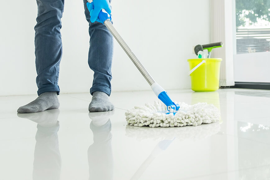 Homem com mop up realizando a limpeza de piso de sua casa