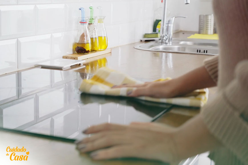 Mulher limpando o fogão da cozinha com produtos de limpeza para casa
