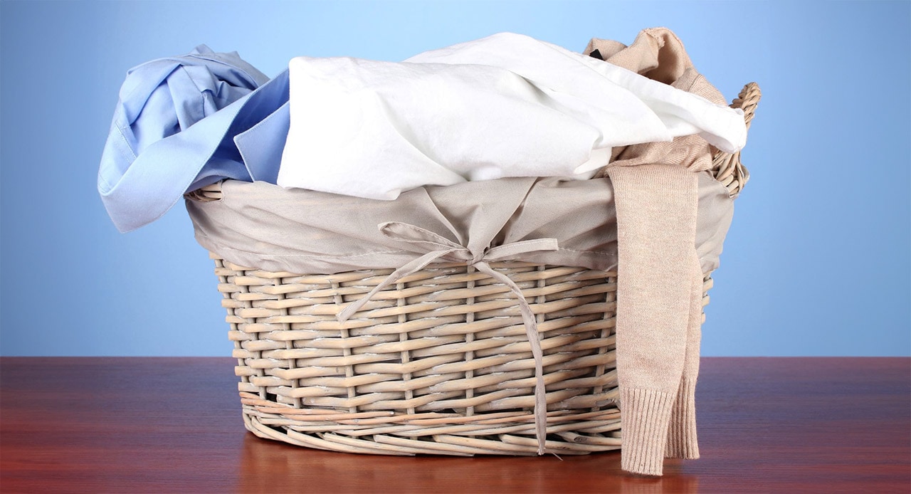 Cesto cheio de roupas esperando lavagem por não saber como tirar mancha de desodorante da roupa.