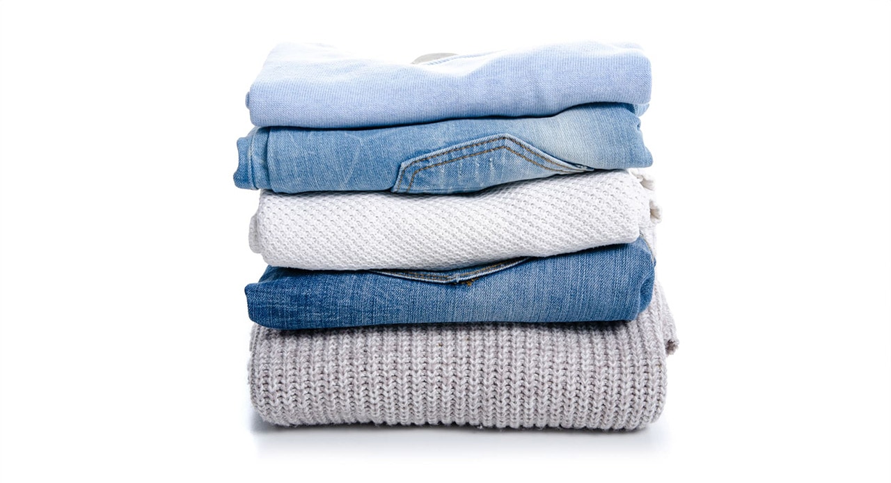 Pilha de roupas dobradas após seguir passo a passo de como tirar mancha de óleo da roupa